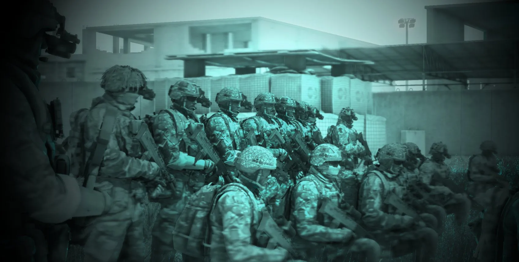 A formation of soldiers in night vision, formed up in ranks under a building's floodlight before an operation.